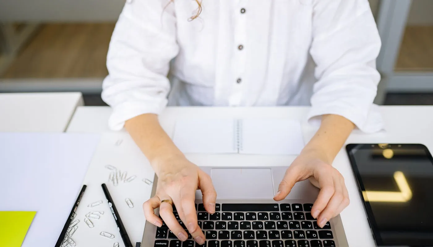 Hands typing on a laptop in a bright modern workspace